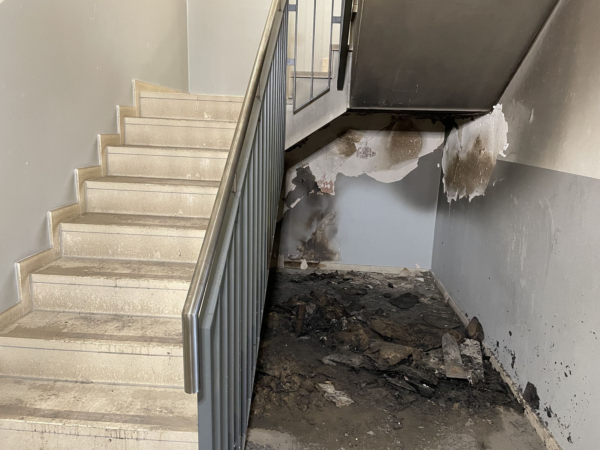 Black ash and soot underneath the stairwell of an apartment building.